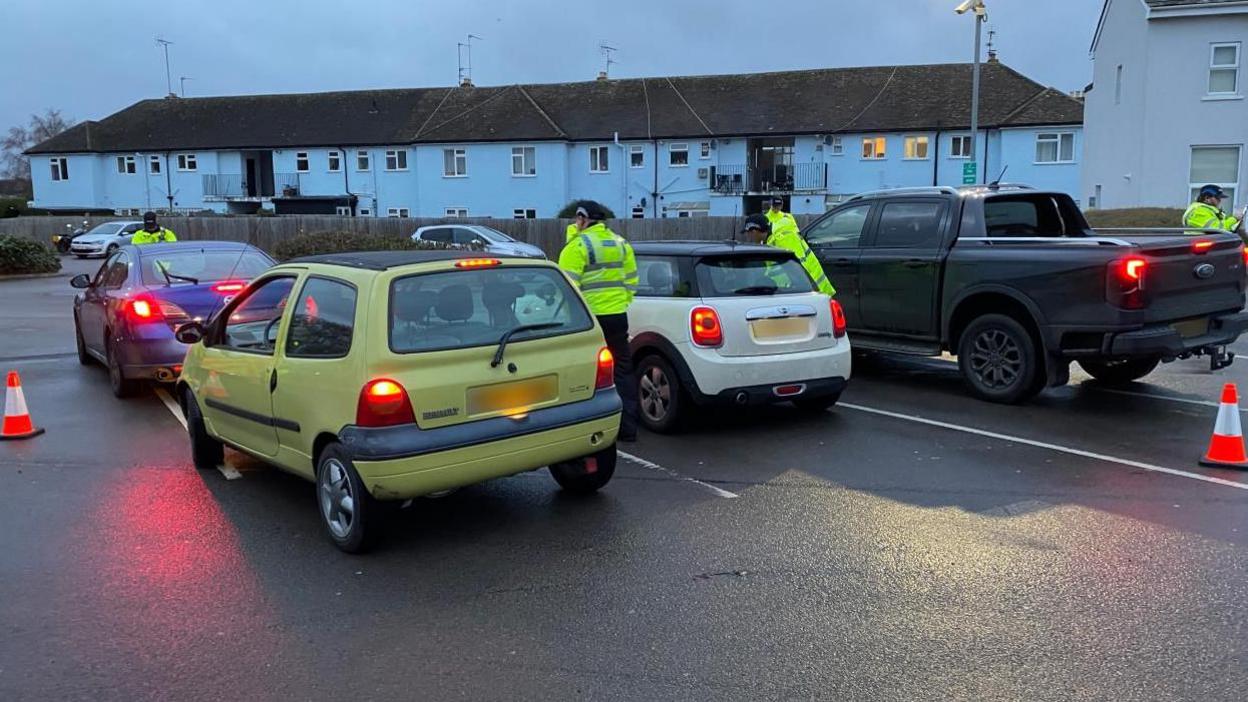 Four vehicles and four Police officers speaking to drivers who have been pulled over for drink drive checks.