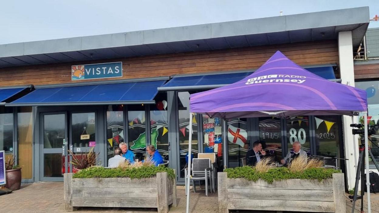A purple topped gazebo with BBC Radio Guernsey on it in front of Vistas Café.