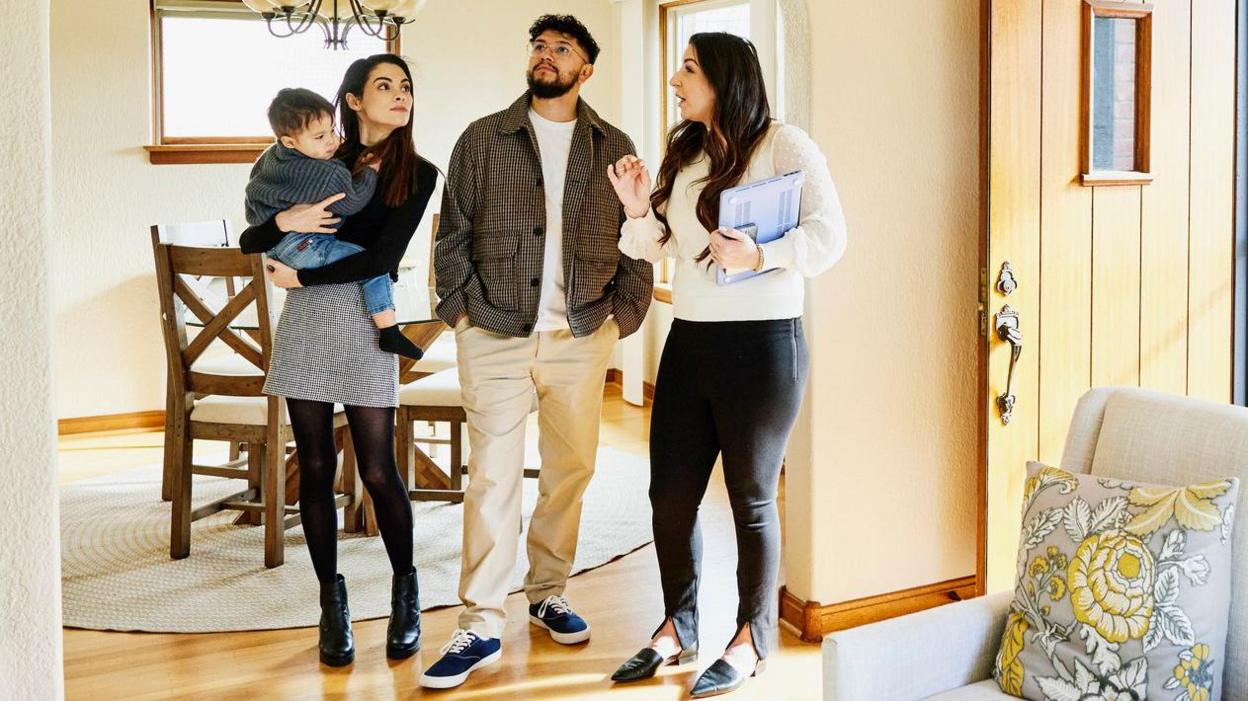 A young family looking at a potential home as the estate agent tells them about its features