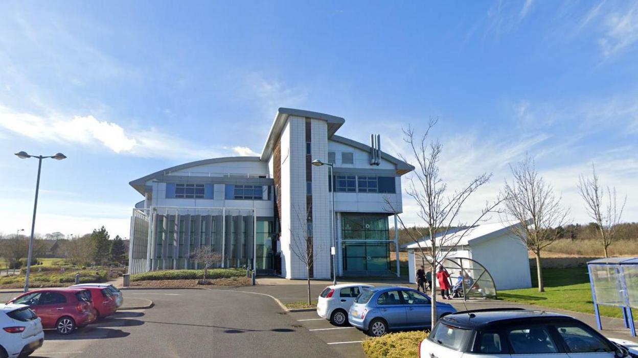 Futuristic looking building and car park in front