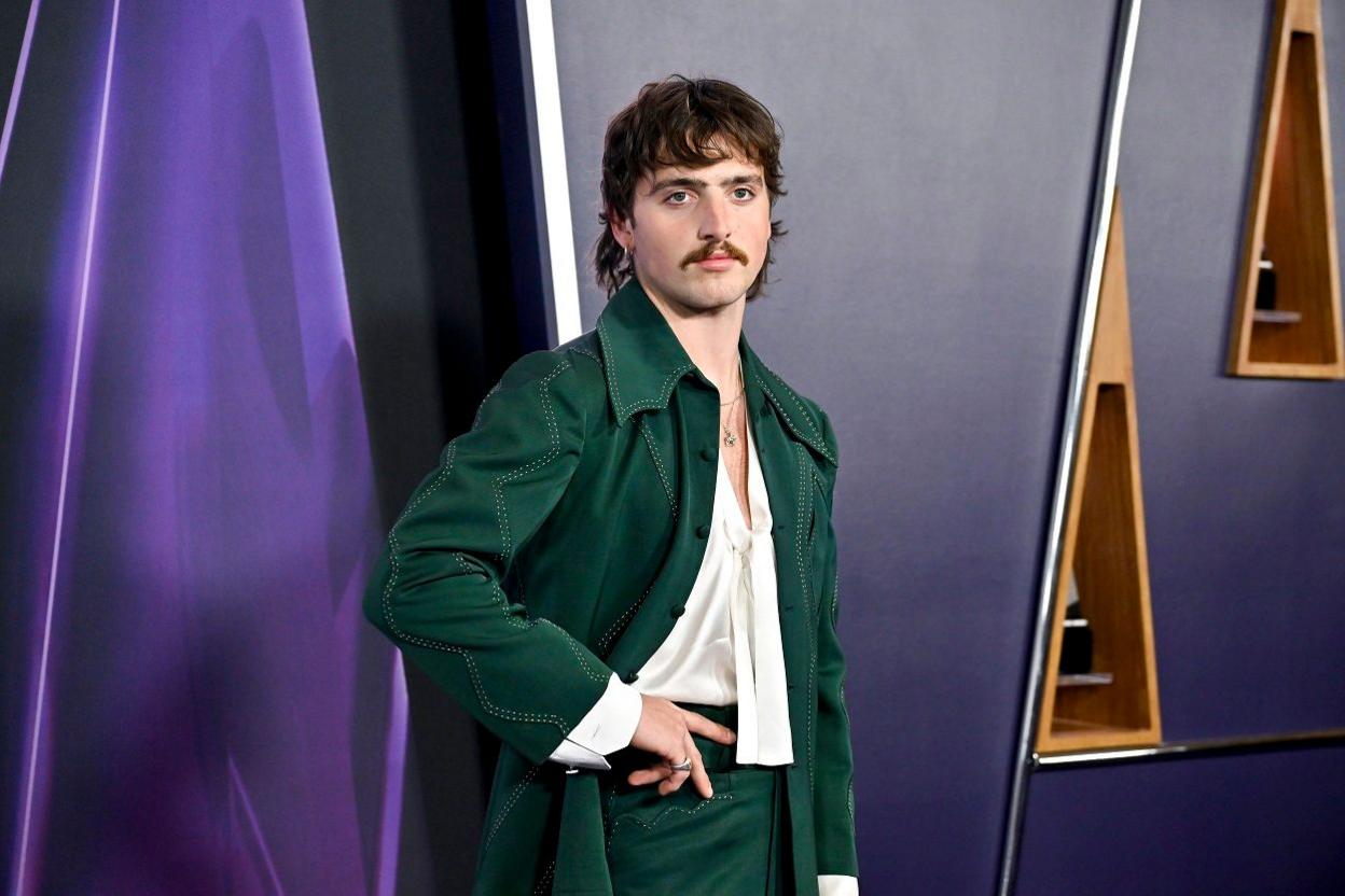 Benson Boone wearing a green suit while posing for pictures on the red carpet