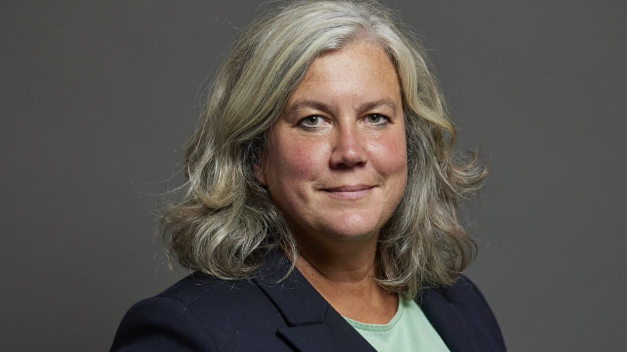 Headshot of Heidi Alexander, who has shoulder-length grey hair and wears a navy blazer and a mint green top.