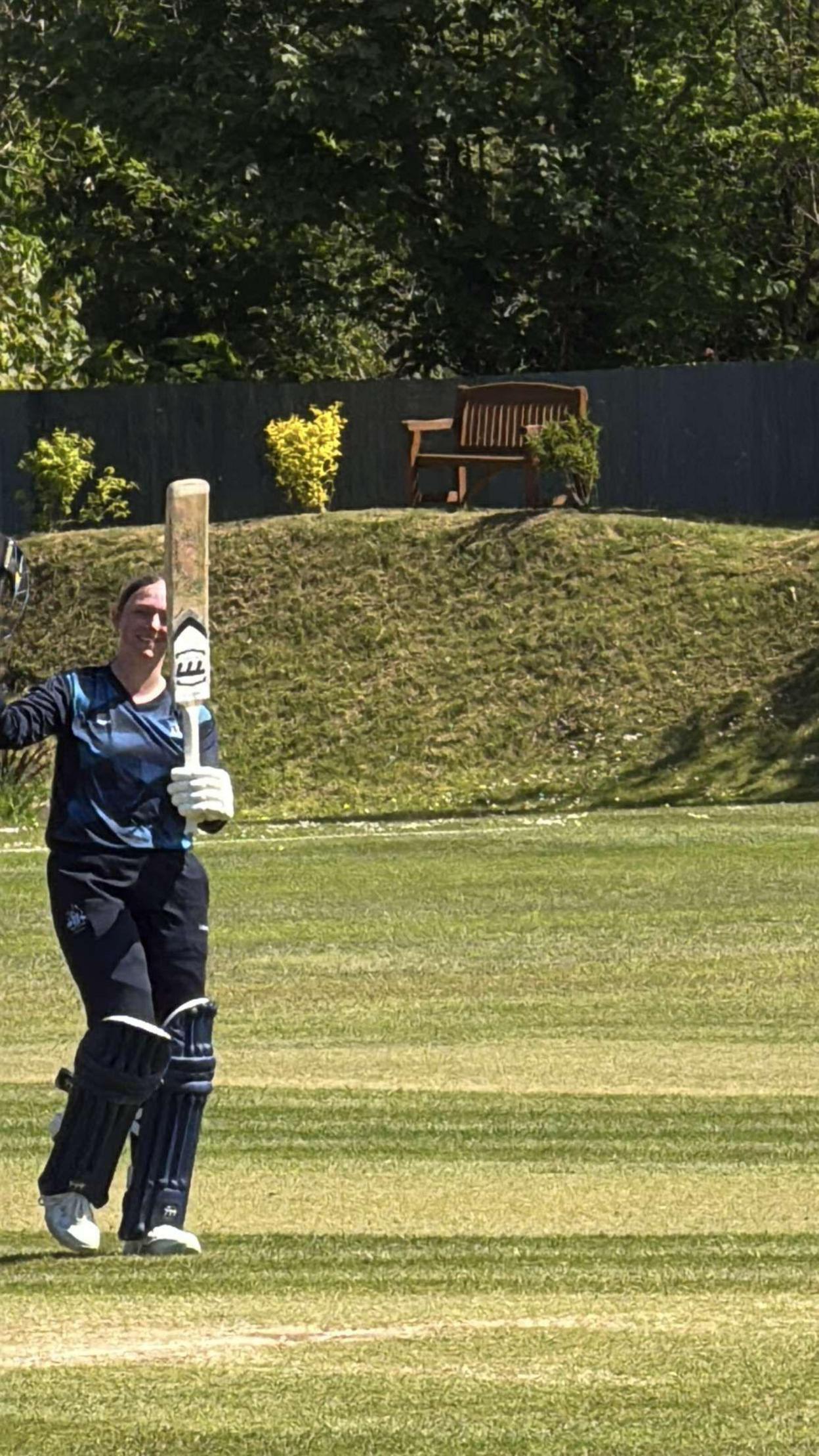 Libby raising her bat after yet another century last season. She is wearing navy cricket kit