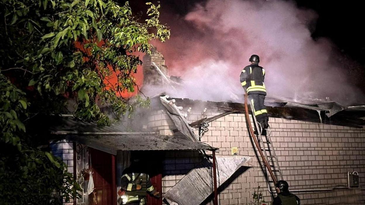 Firefighters work at a site of a strike on a home near Kyiv