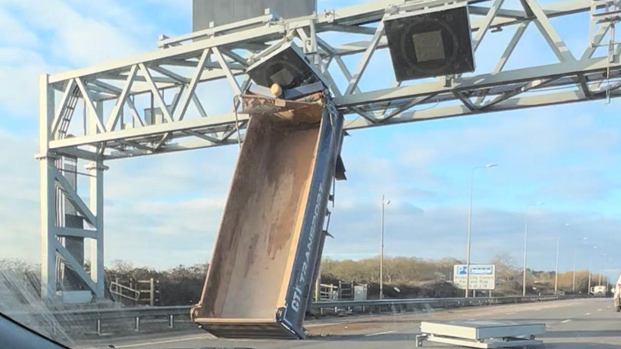 The tipper truck bed seen stuck vertically in the M5 gantry, with the motorway now clear of traffic