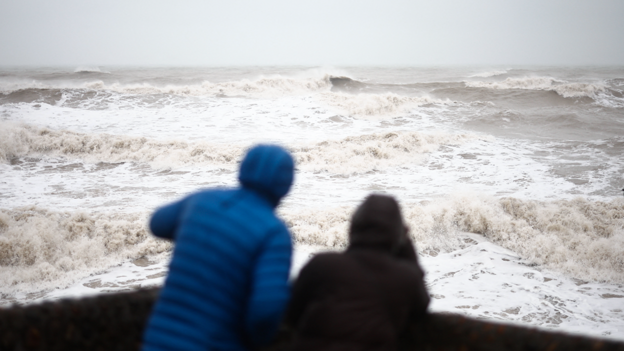 Two people looking out to a very rough sea