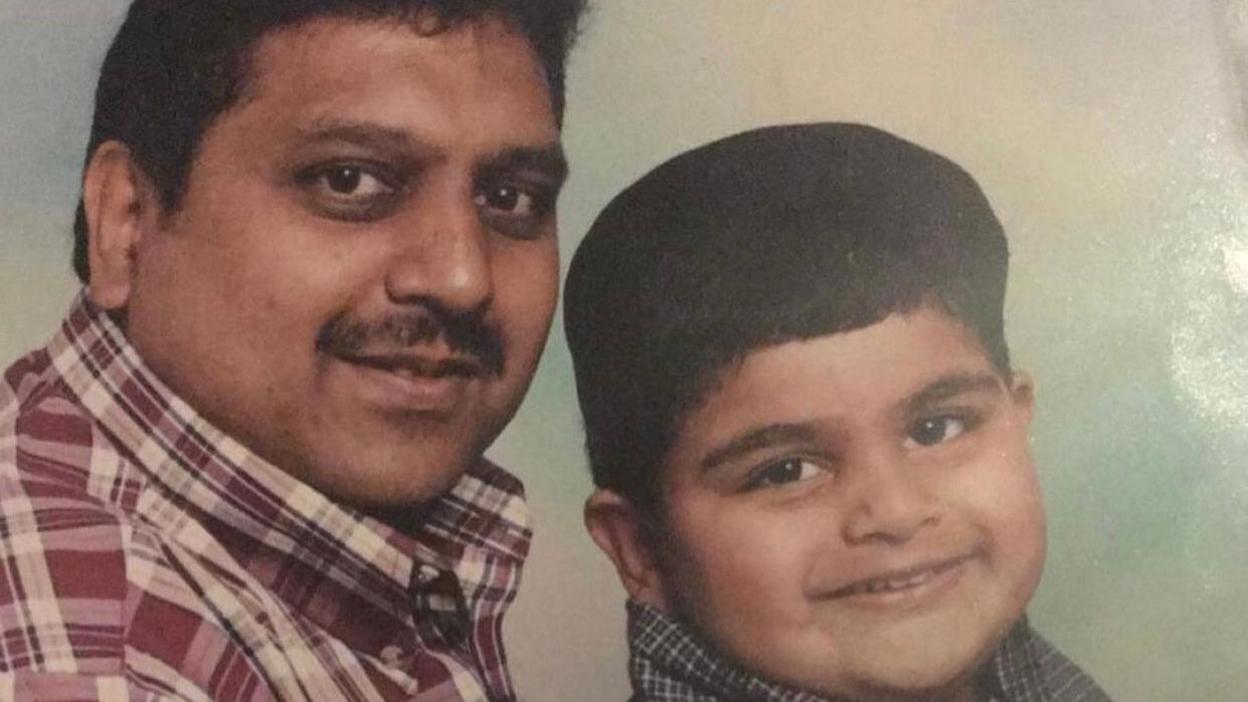 An old family photo showing Ibrahim wearing a red checked shirt and a young Jameel smiling at the camera