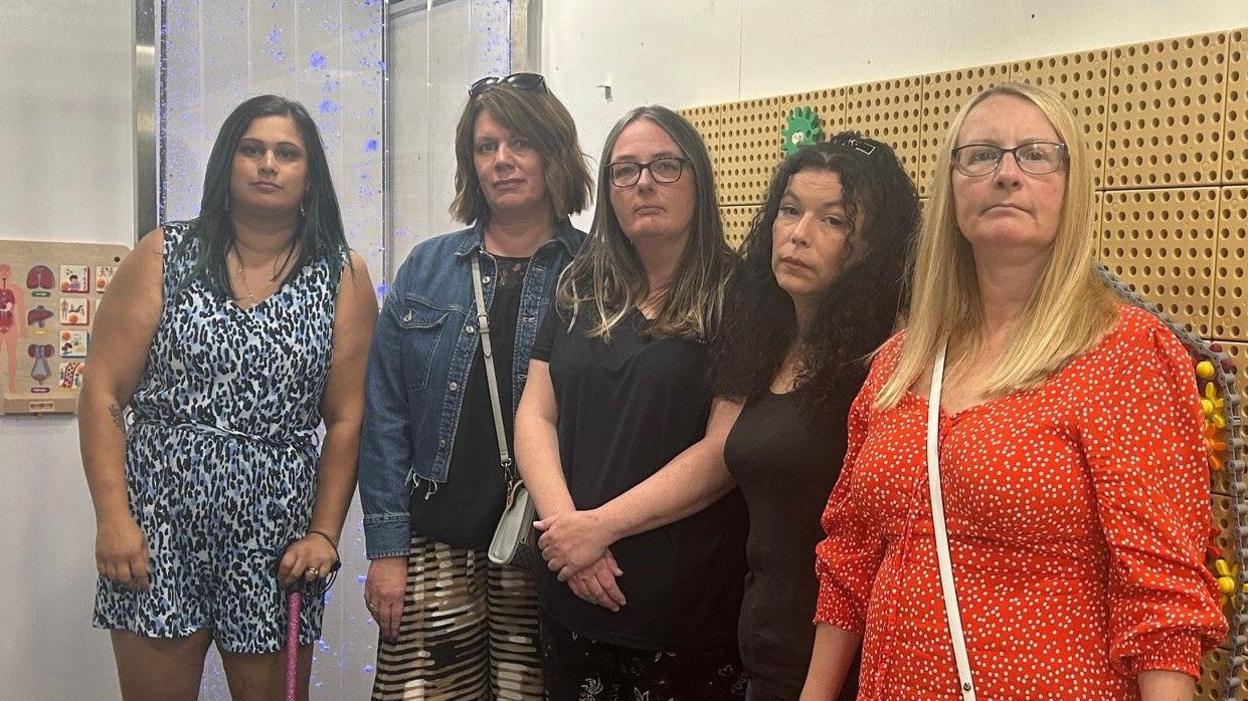 Five mothers standing in a play centre looking a the camera