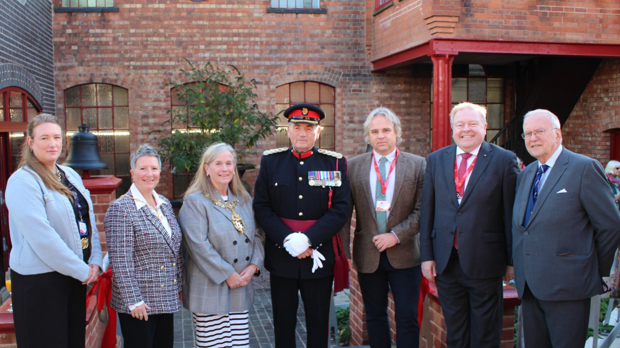 A line of men and women including the vice lord lieutenant of Leicestershire in a dark blue and red military style uniform