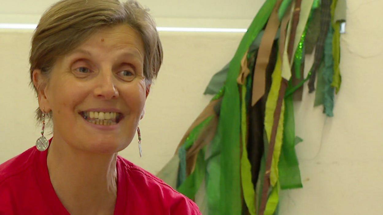 Sue Caudle, smiling, wearing a red T-shirt