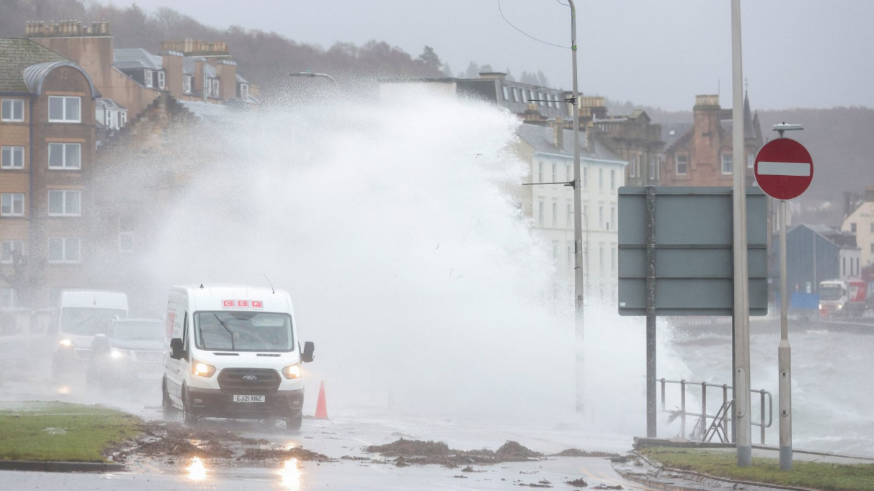 Two vans and a car being swamped with water on the front at Oban