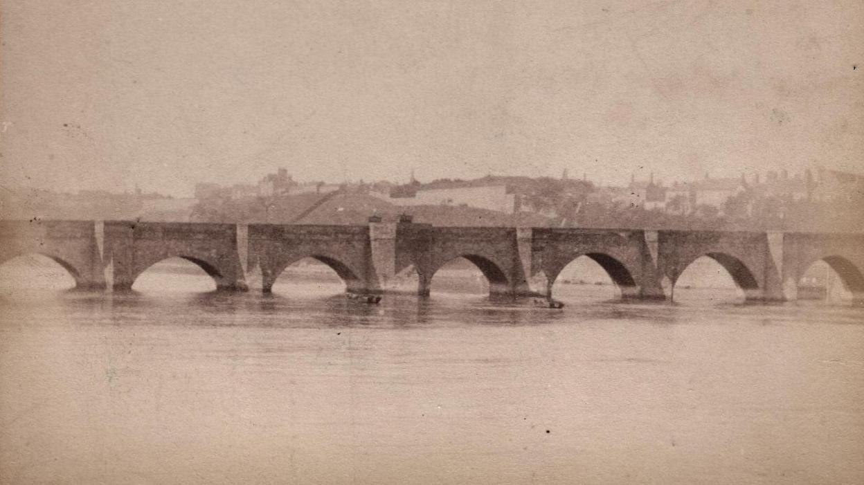 A grainy image of the bridge with buildings in the background