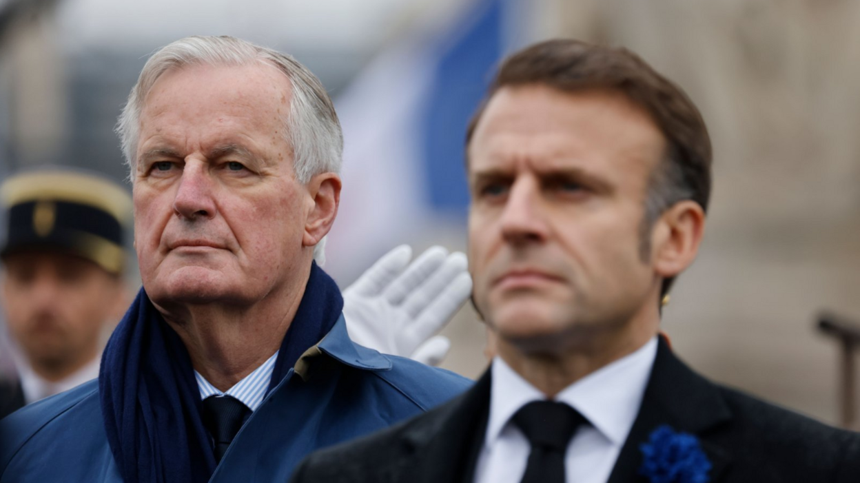 Barnier, in a blue overcoat and navy scrarf, stands next to Macron, who is dressed in a black suit, as they both look solemn during WWI commemorations last month 