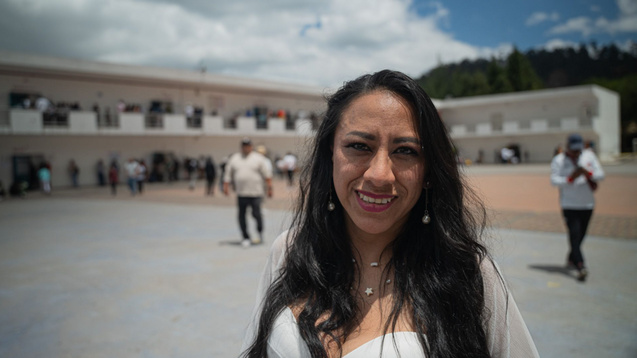 Ecuadorian voter Gabriela Cajo posses for a photo next to a big open square in the background which appears to be where people are casting their votes