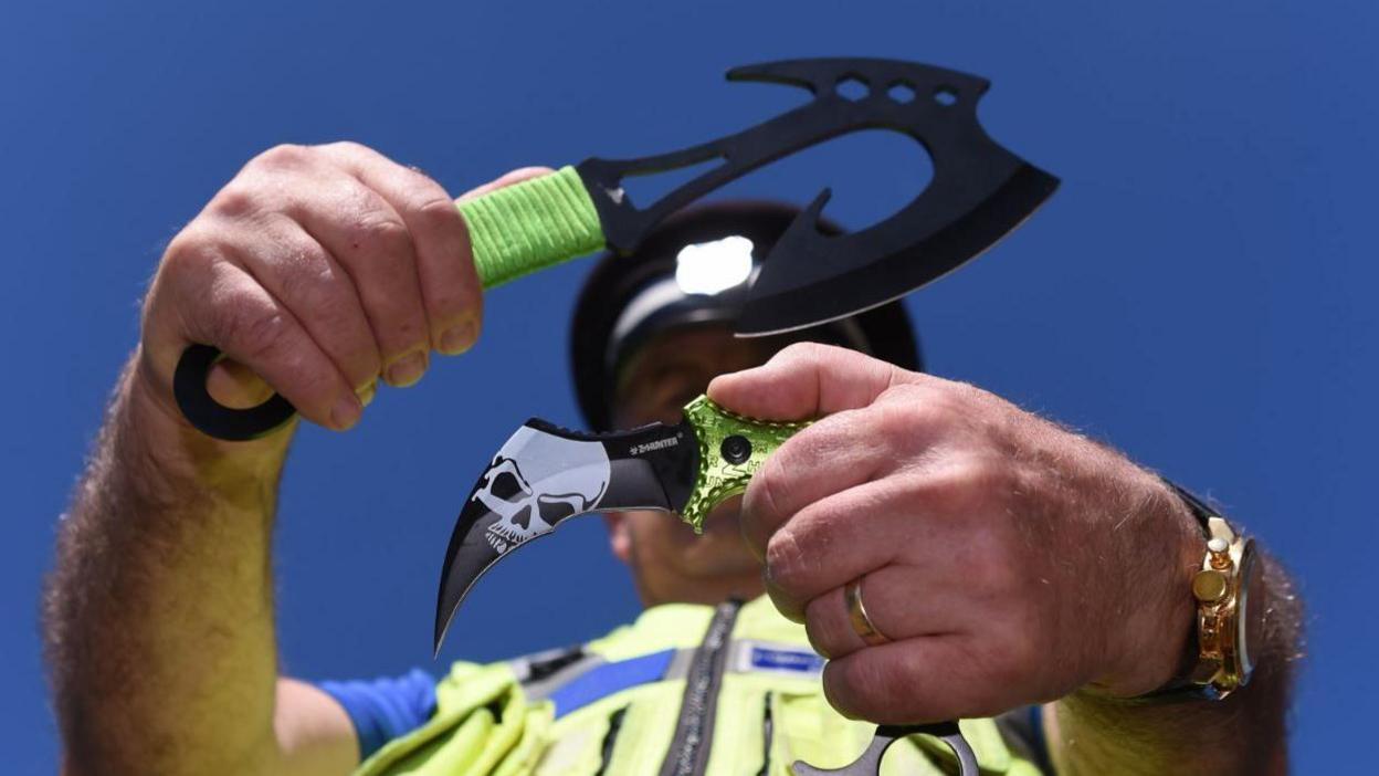 Police officer holding knives