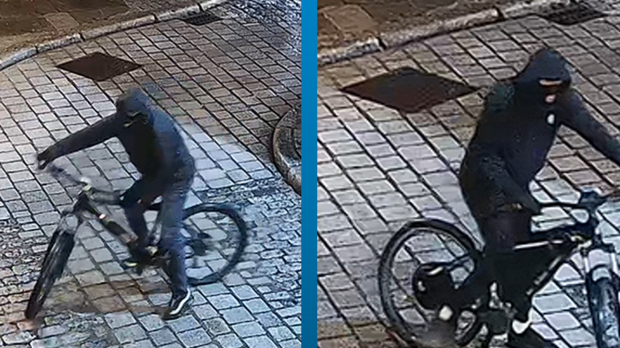 CCTV footage of two men wearing all black and on a bicycle. They are both wearing black balaclavas and are riding the bicycles.