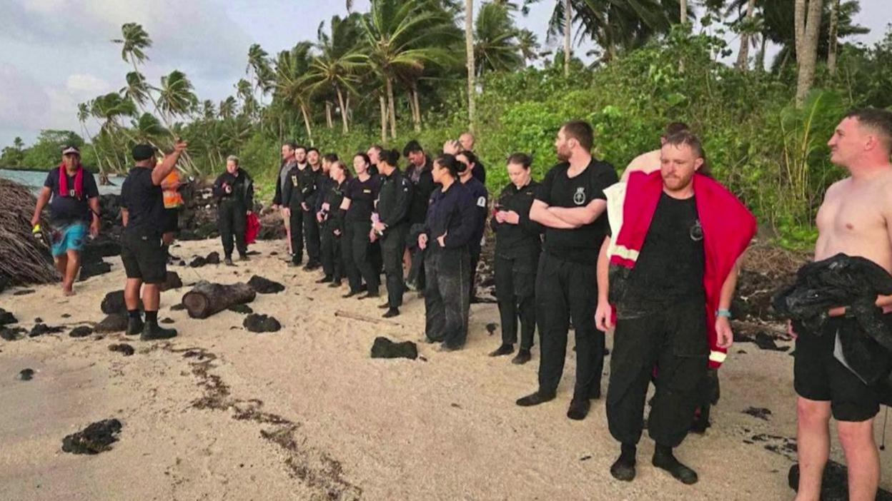 Crew and passengers of HMNZS Manawanui on a Samoan beach after being rescued.