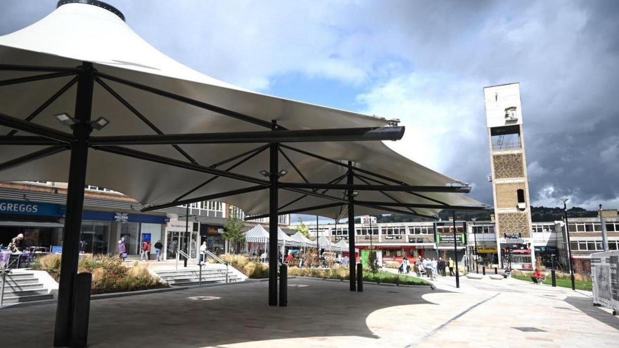 Shipley Market Square including a concrete clock tower and covered canopies with shops around the outside.