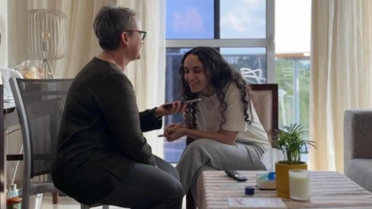 Mandy and Emily Damari sitting in a room and speaking on a phone