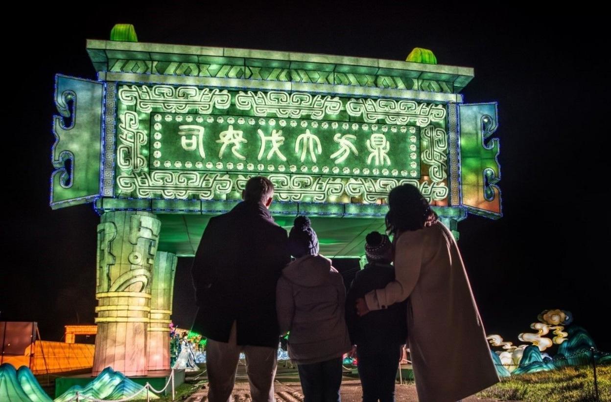 A group pf people look up at a giant green illumination as part of the Longleat Festival of Light