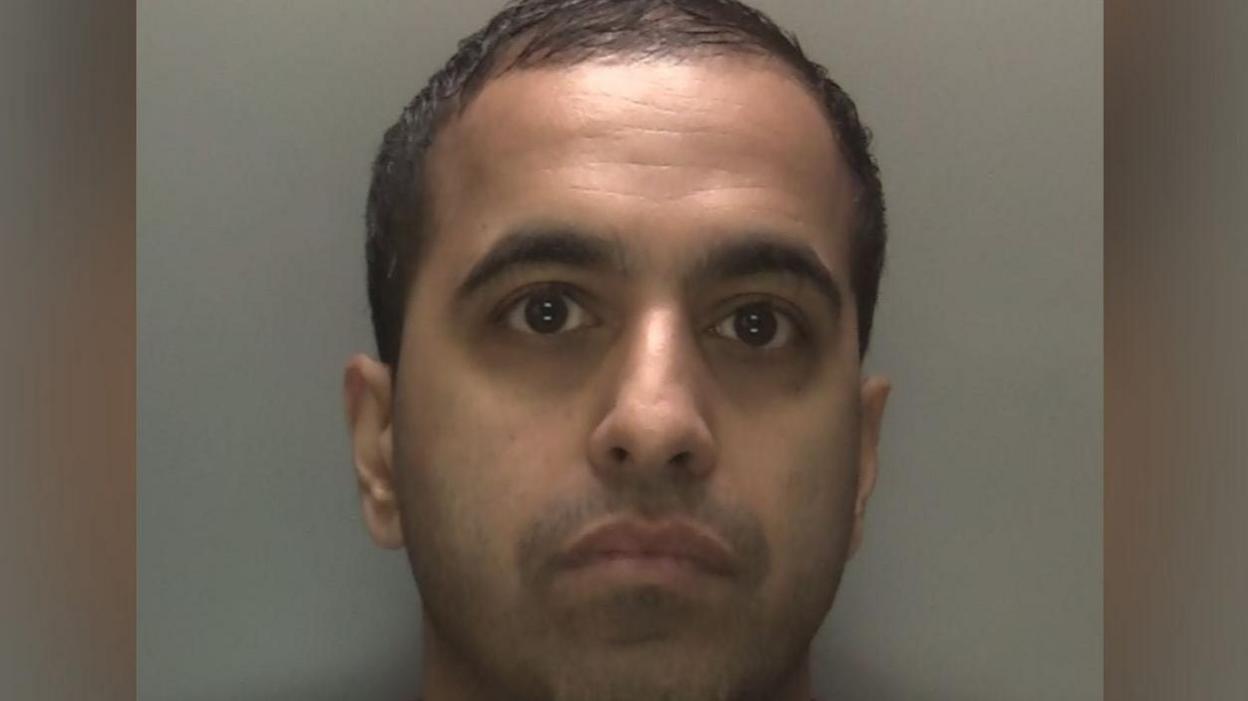 An image of a man in a red top in front of a grey background