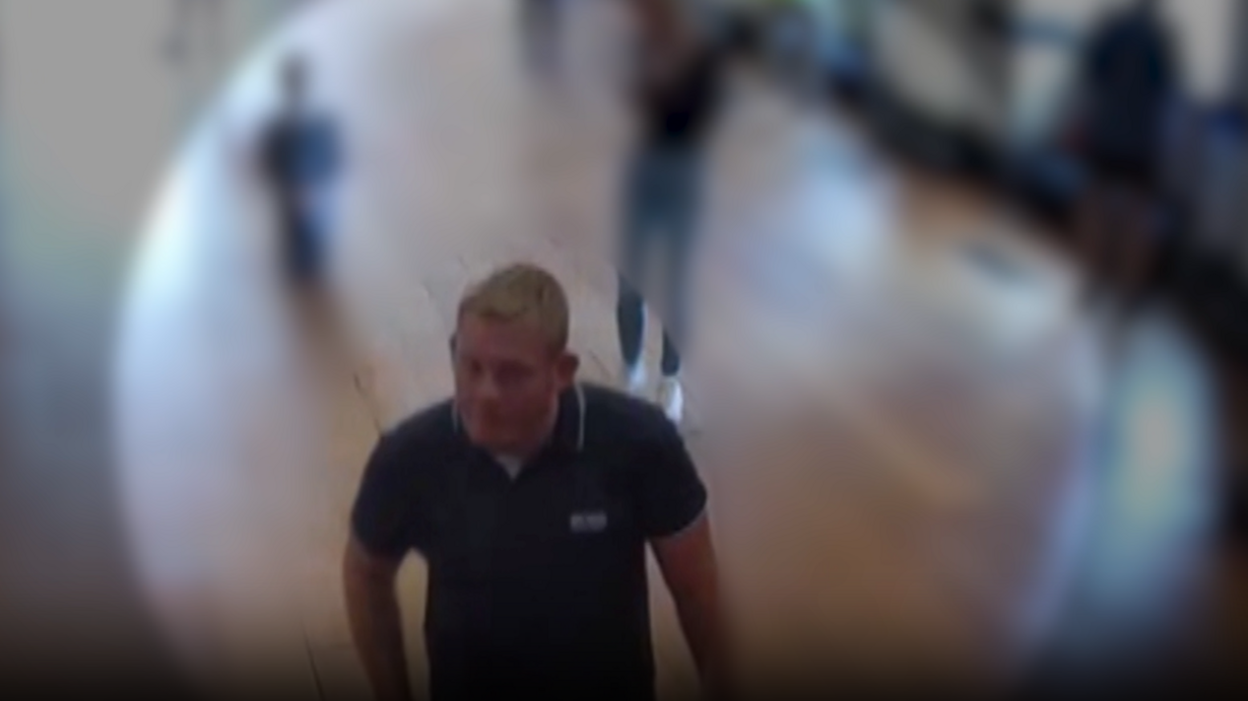 A CCTV image of Michael Jones, wearing a blue polo shirt, visiting Blenheim Palace, with figures in the background blurred