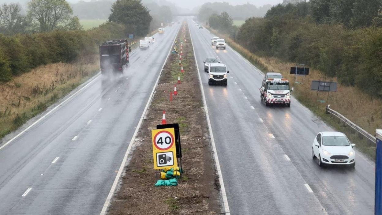 View from a bridge showing cars driving through rain on the A63 in East Yorkshire with central barriers removed and a 40mph speed sign