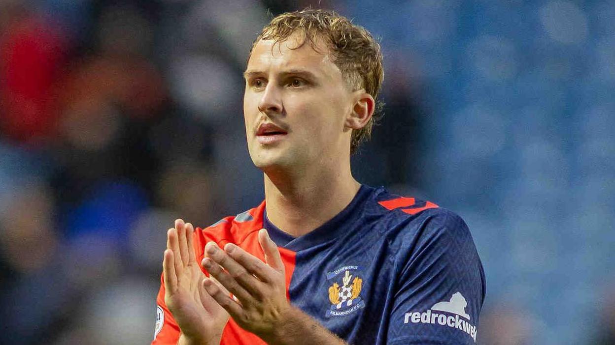 Zac Williams, wearing Kilmarnock's red and blue away kit, claps fans after a Scottish Premiership game against Rangers at Ibrox