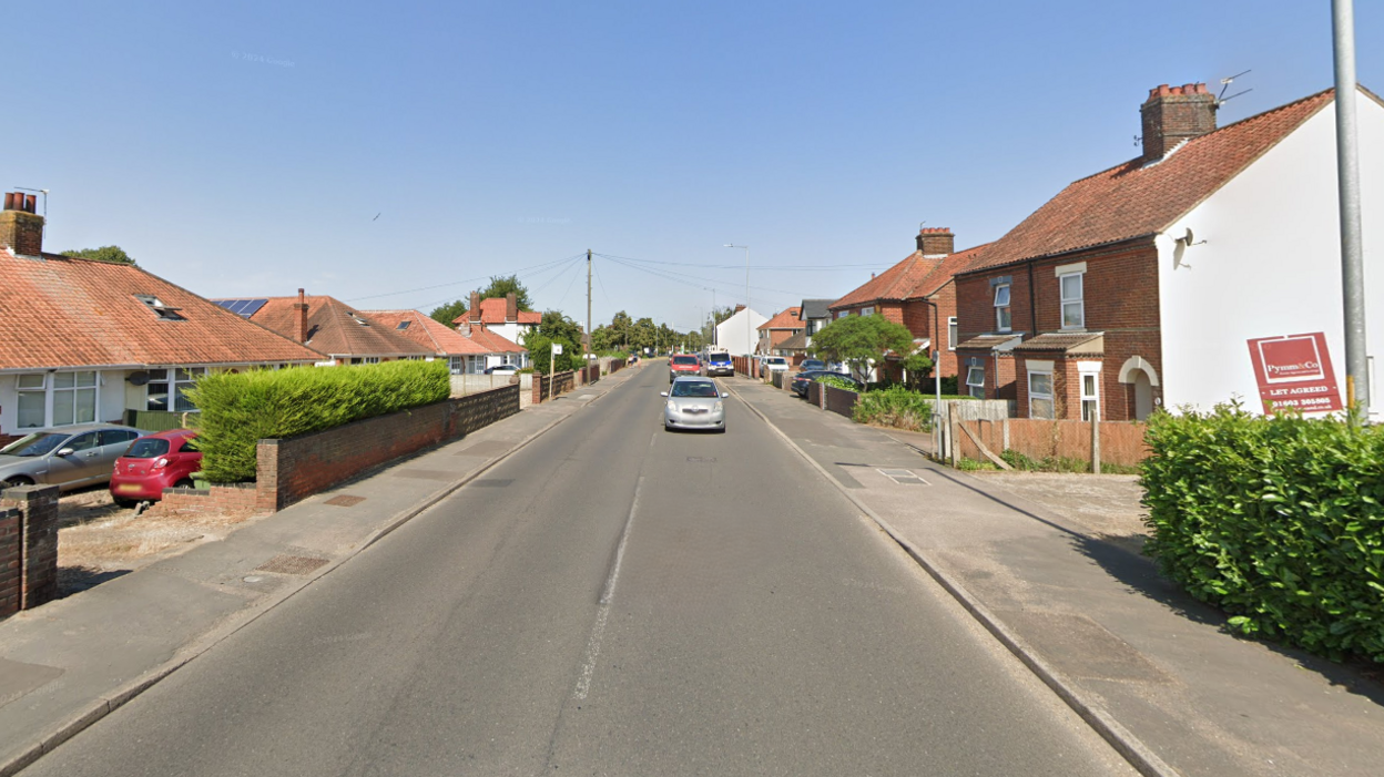 A street view image of cars driving along North Walsham Road which is lined by houses and bungalows