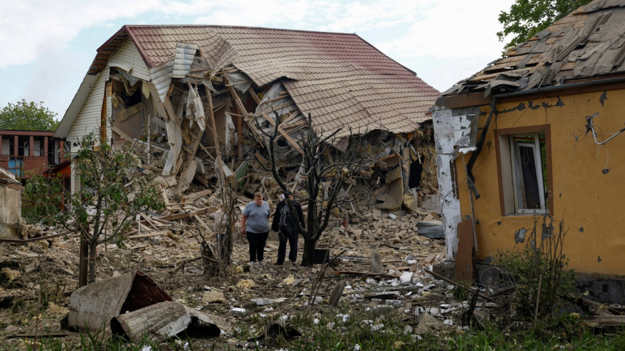 Two men stand next to their homes which were struck by a Russian drone in an attack outside of Kyiv on 18/5/2025