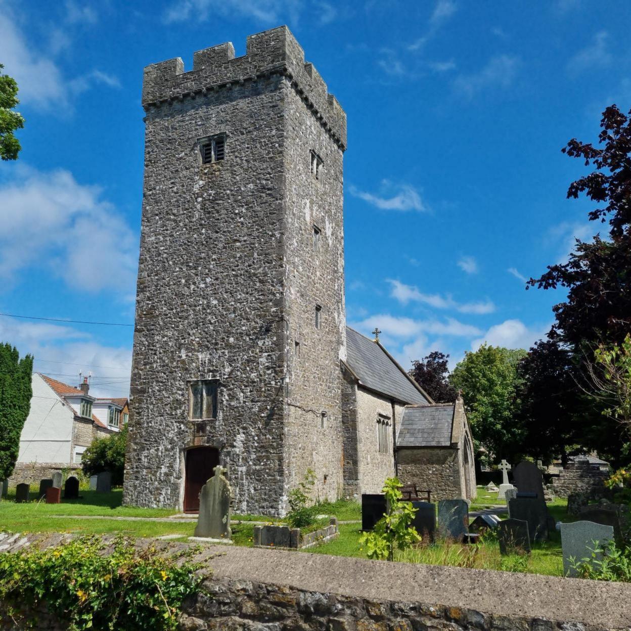 St Cattwg's Church in Llanmaes surrounded by green grass with a blue sky behind it