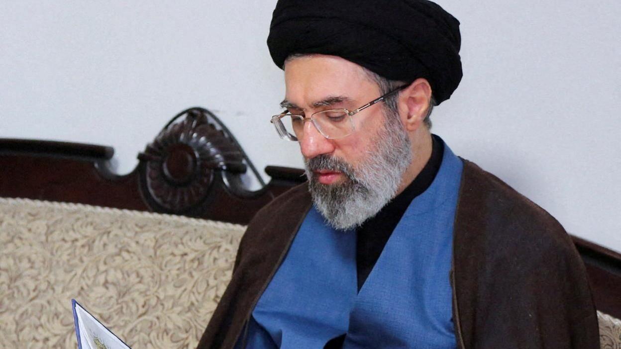 Mojtaba Khamenei reads from a book.