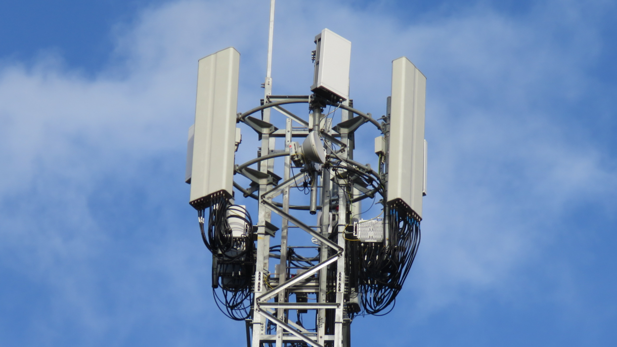 A mobile phone mast with various dishes and antenna against a blue sky