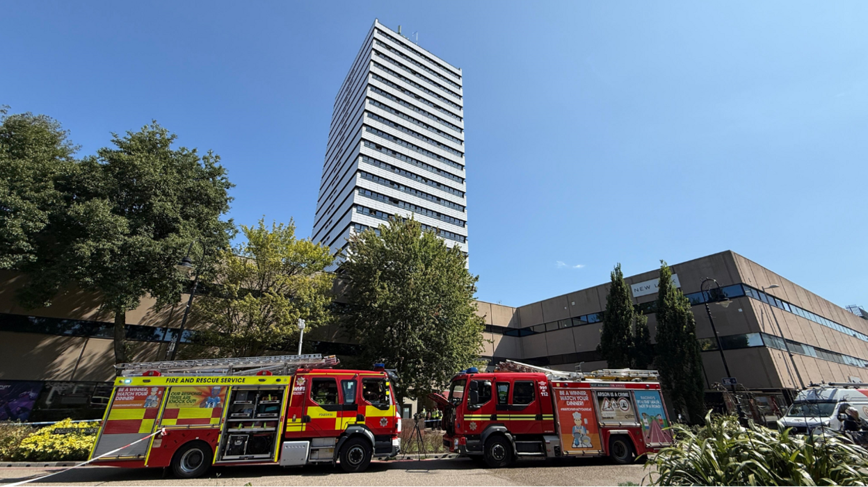Two fire engines parking at the front of a tall tower block