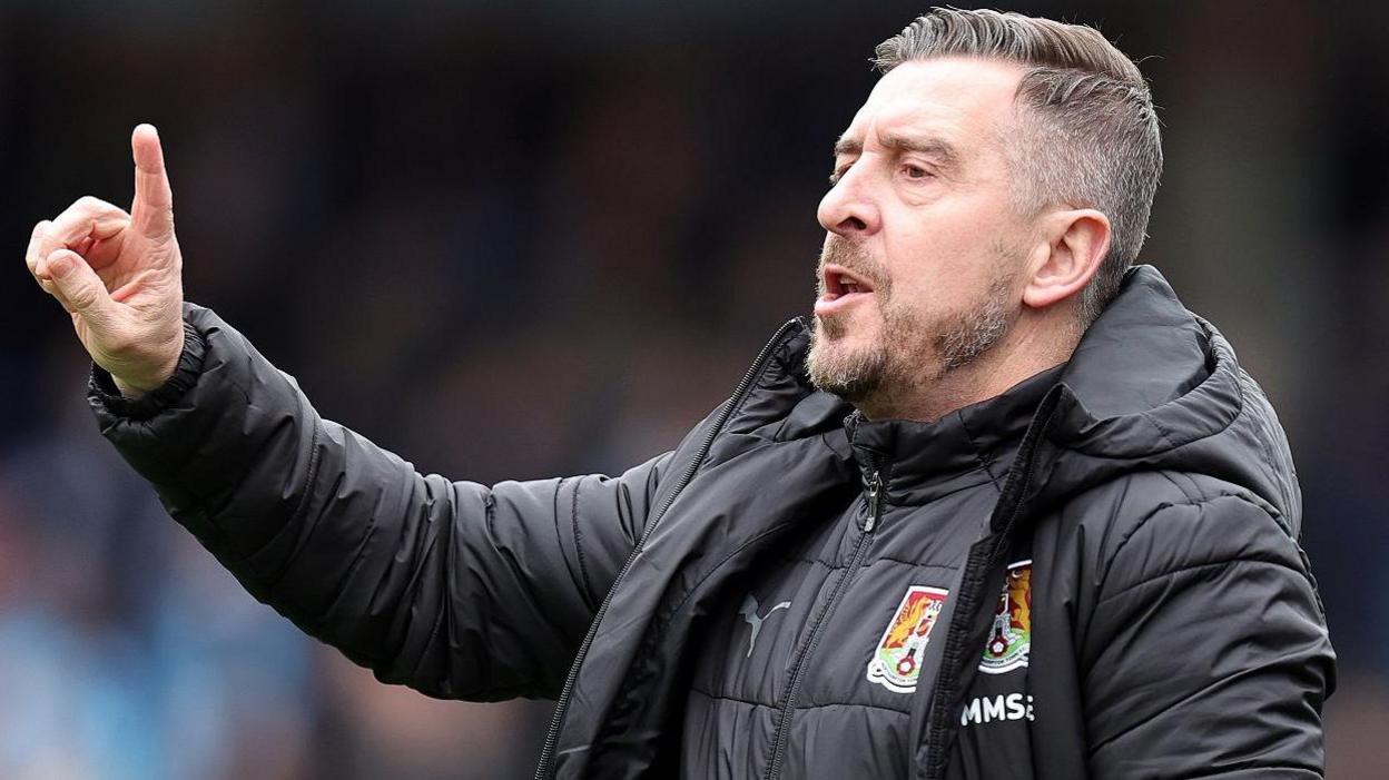 Northampton Town boss Jon Brady signals to his players during a League One game