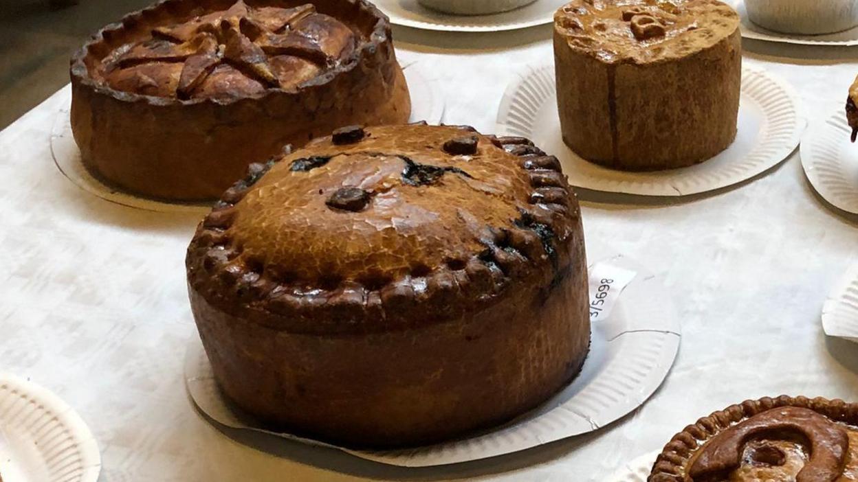 Several different shaped pork pies on paper plates