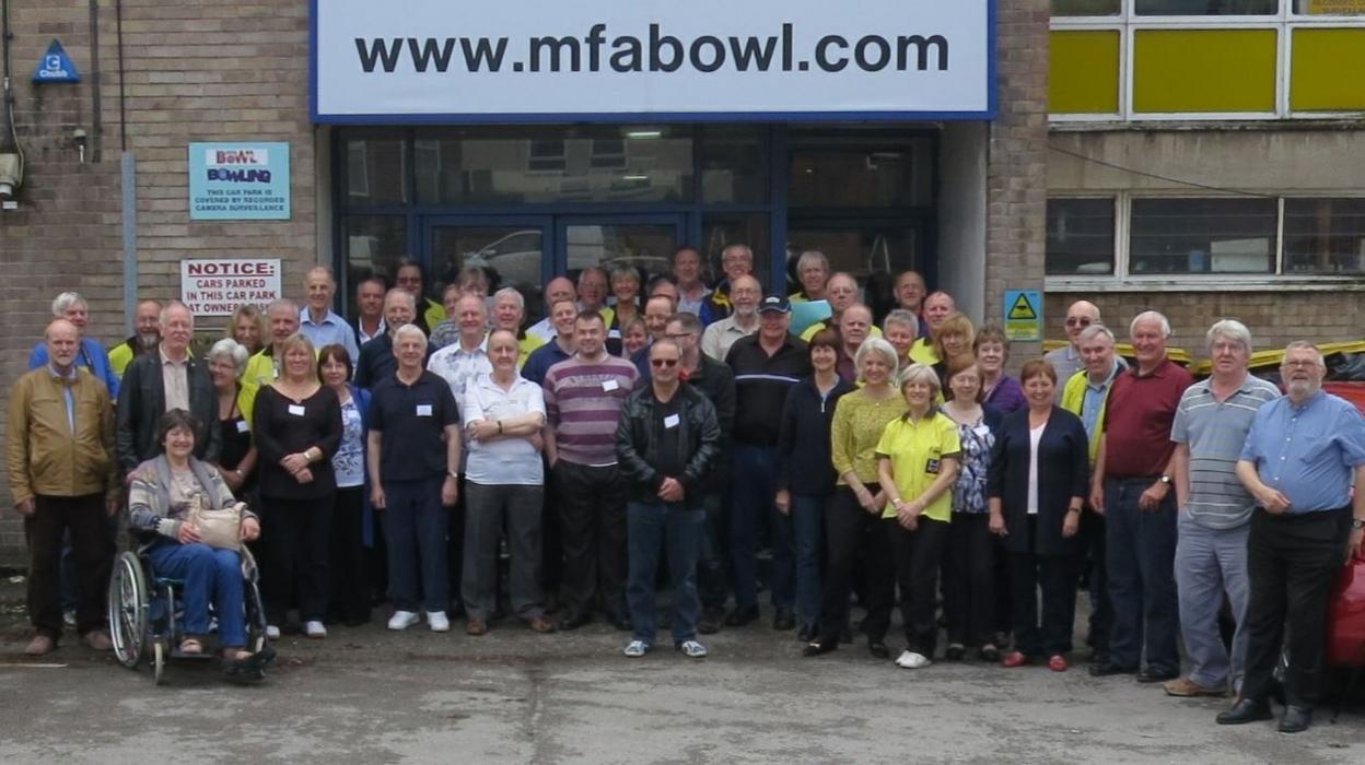 A group of about 100 people standing together outside a bowling alley.