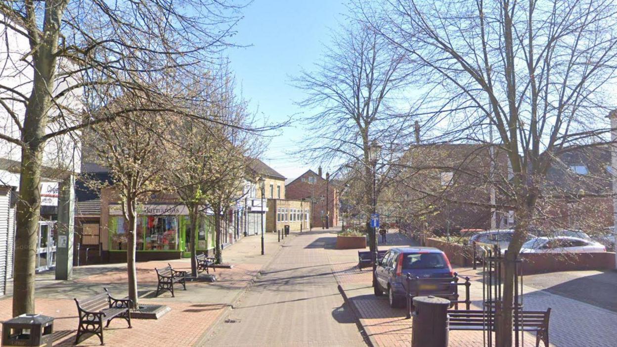 Staveley High Street, lined with trees and benches.