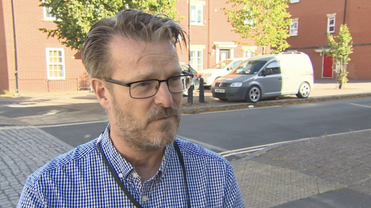 Councillor Chris Watt being interviewed on a road with cars behind him. 