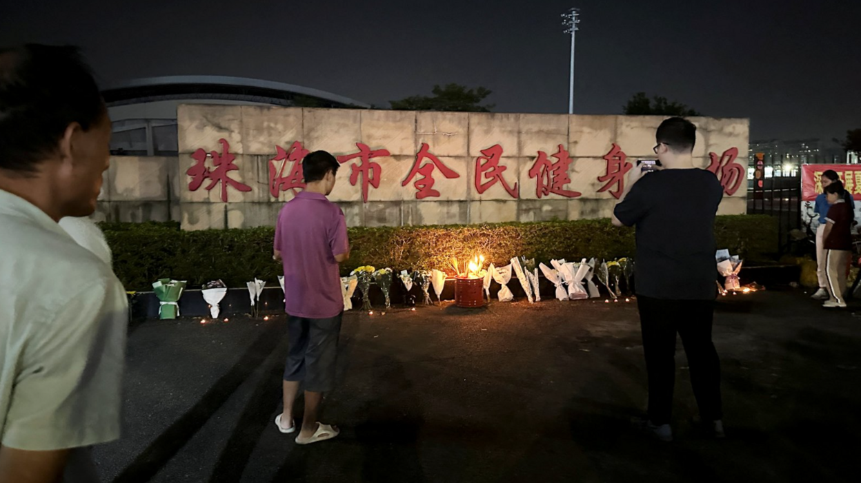 Mourners bow their heads while visiting the stadium on Tuesday, where a string of floral tributes line the perimeter