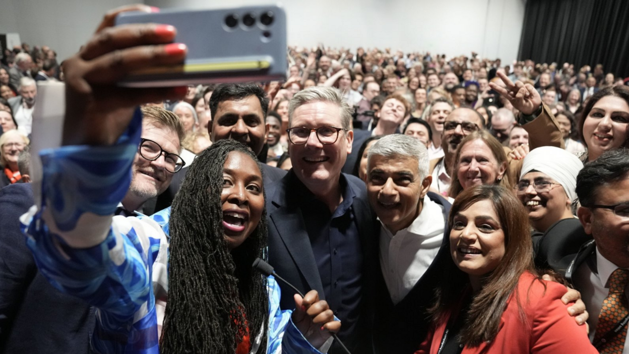 Prime Minister Sir Keir Starmer poses for a selfie with Dawn Butler, MP for Brent East and Mayor of London Sadiq Khan at a reception during the Labour Party Conference in Liverpool. A huge crowd of people stand behind the Labour politicians