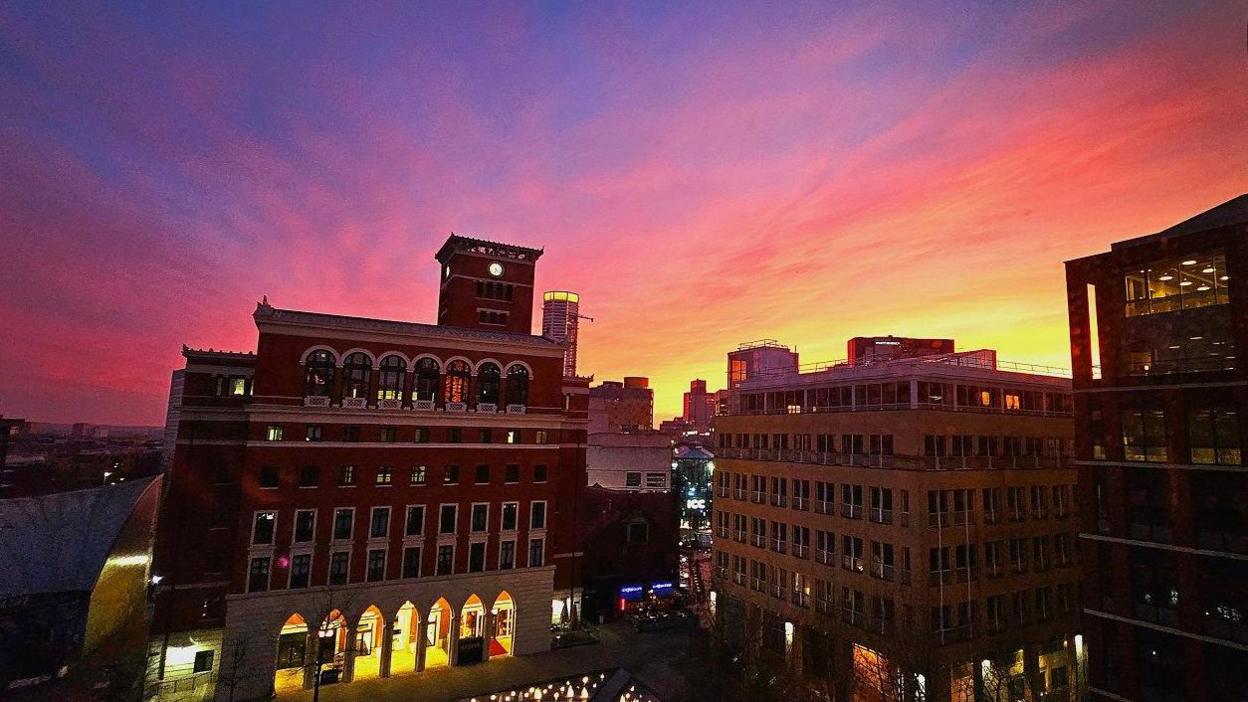 Buildings lit up from behind by rays of red, yellow and orange.