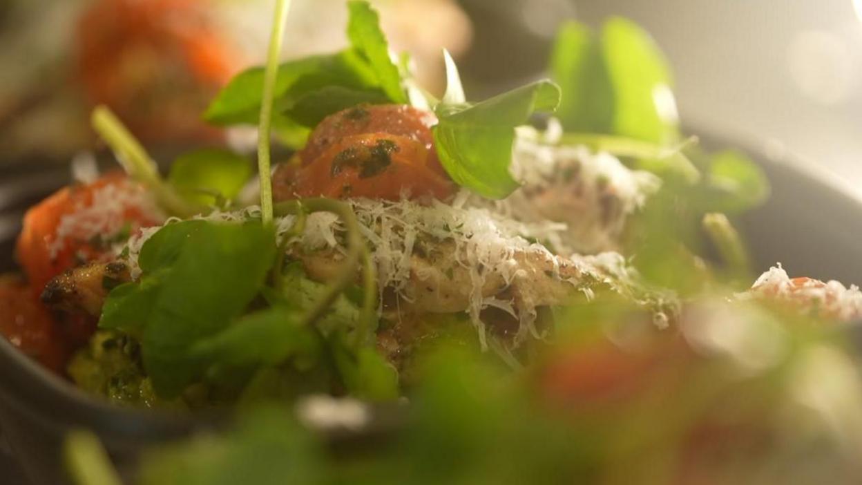 A close up of a salad with chicken and tomatoes 