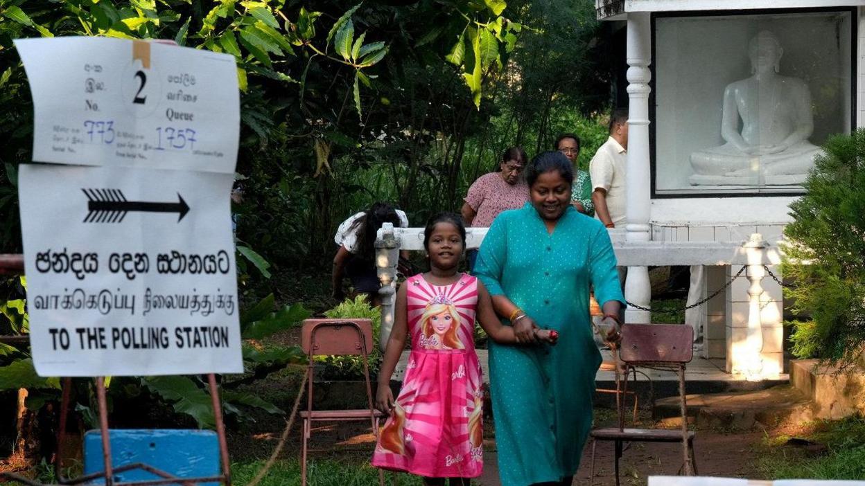 A woman walks with her daughter as she leaves a polling station after casting her vote on the day of the parliamentary election, in Colombo, Sri Lanka, November 14, 2024.