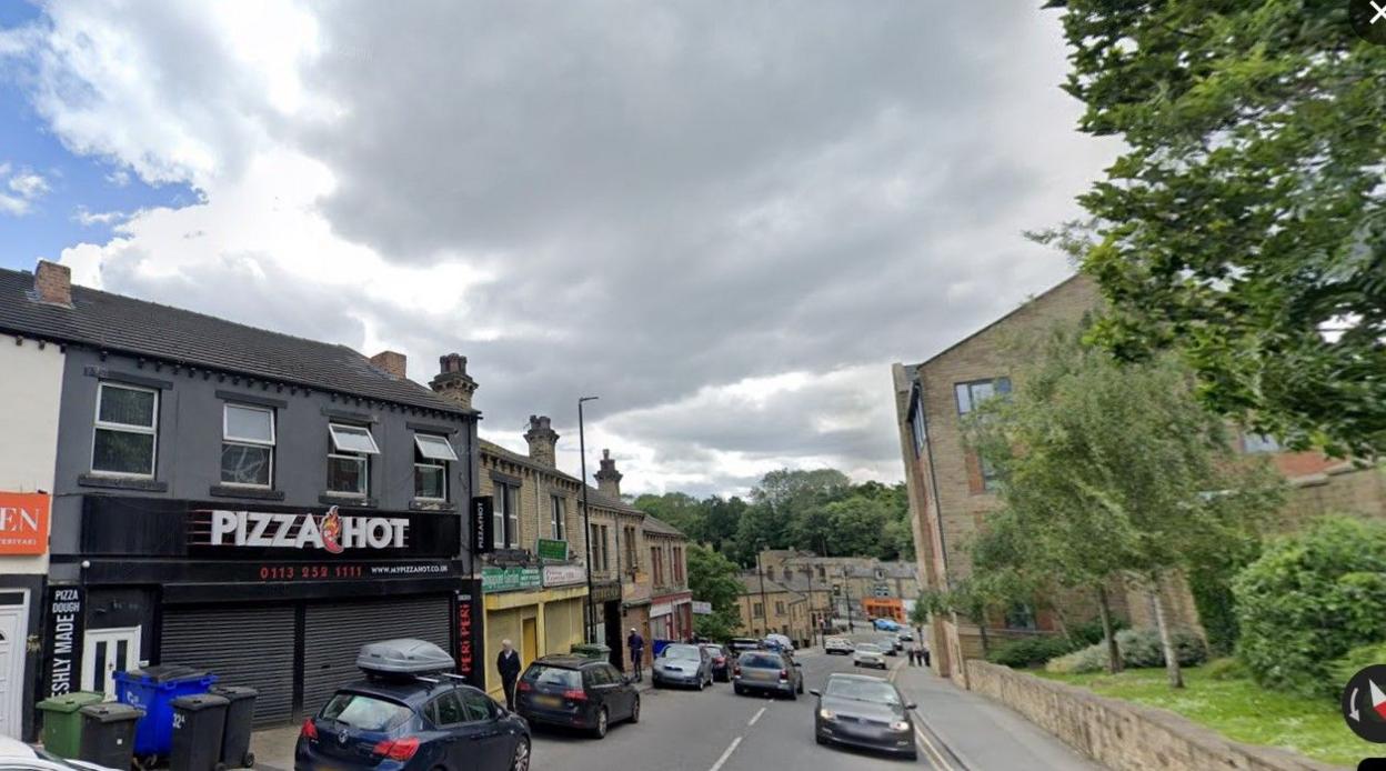 View down Chapel Hill in Morley with pizza takeaway in the left foreground and terraced housing further along the street