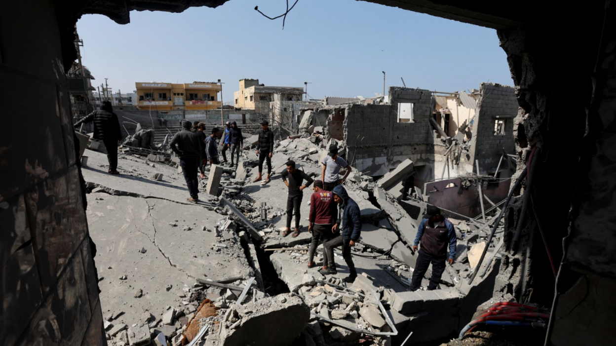 Palestinians inspect the rubble and destruction of what used to be a home after Monday night's airstrikes by Israel's military - seen through a large hole in a building