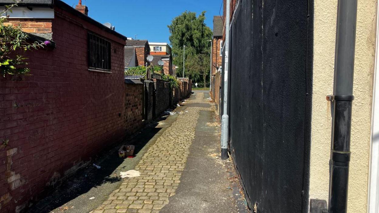 Fletcher Street. An alley is shown with several pieces of rubbish dumped in it. 