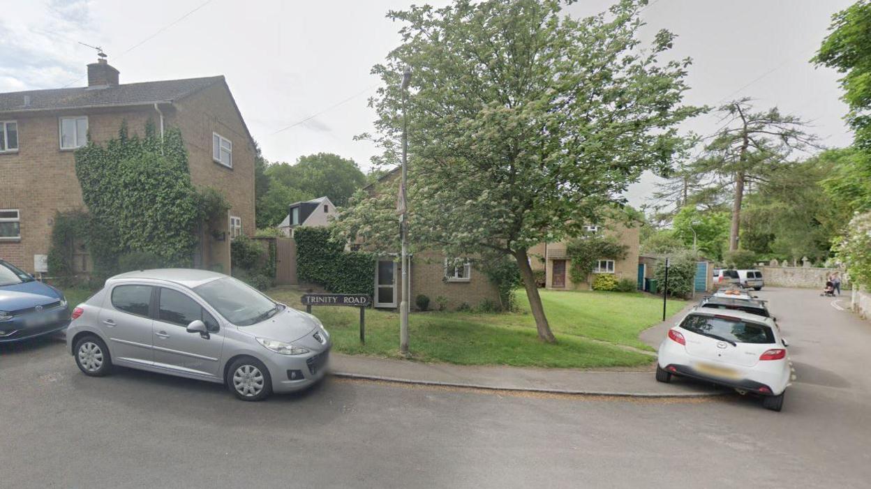 A residential street with a line of cars parked halfway up the pavement