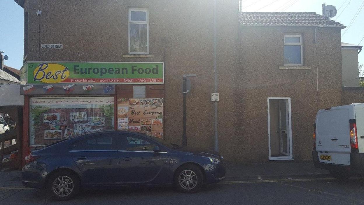 Outside of the Best European Food shop with a car outside