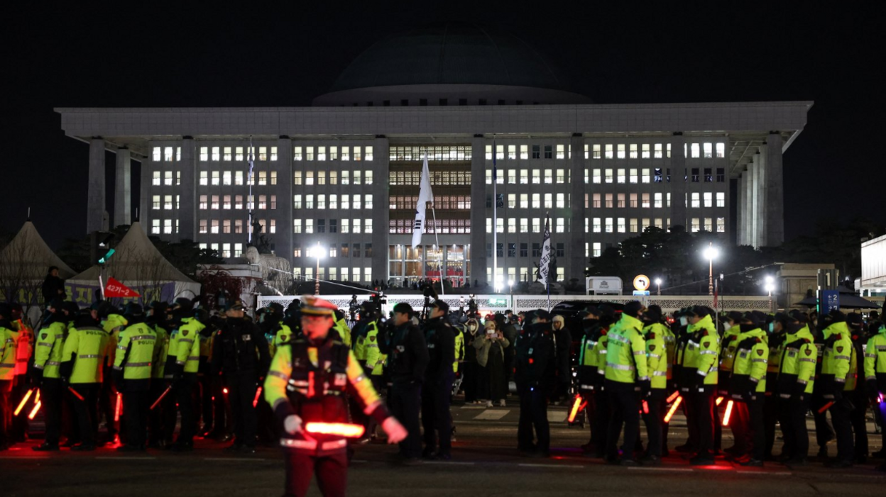 Dozens of police officers in yellow hi vis jackets gather outside the National Assembly in Seoul 